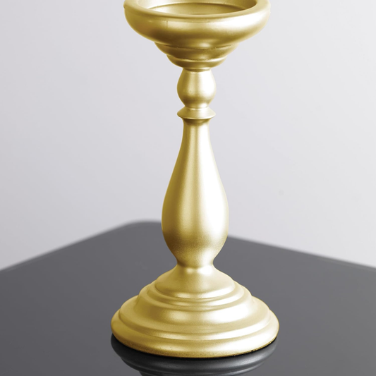 Gold candle holder on a reflective surface with a gray background