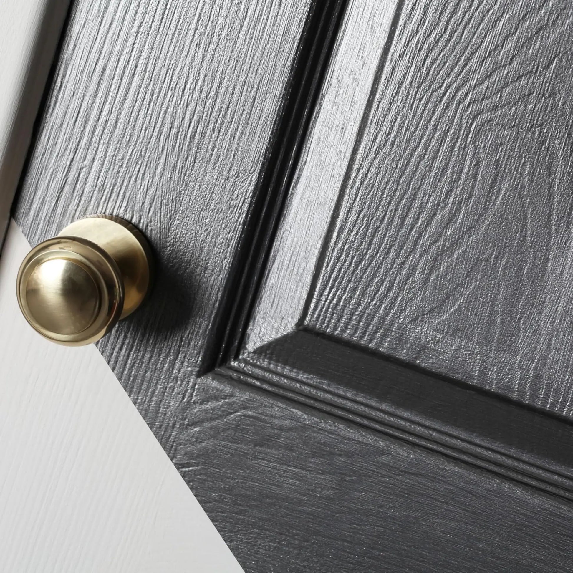 Close-up of a gray wooden door with a gold doorknob