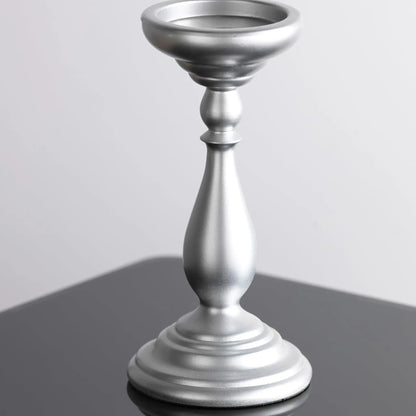 Silver candle holder on a reflective surface with a light gray background