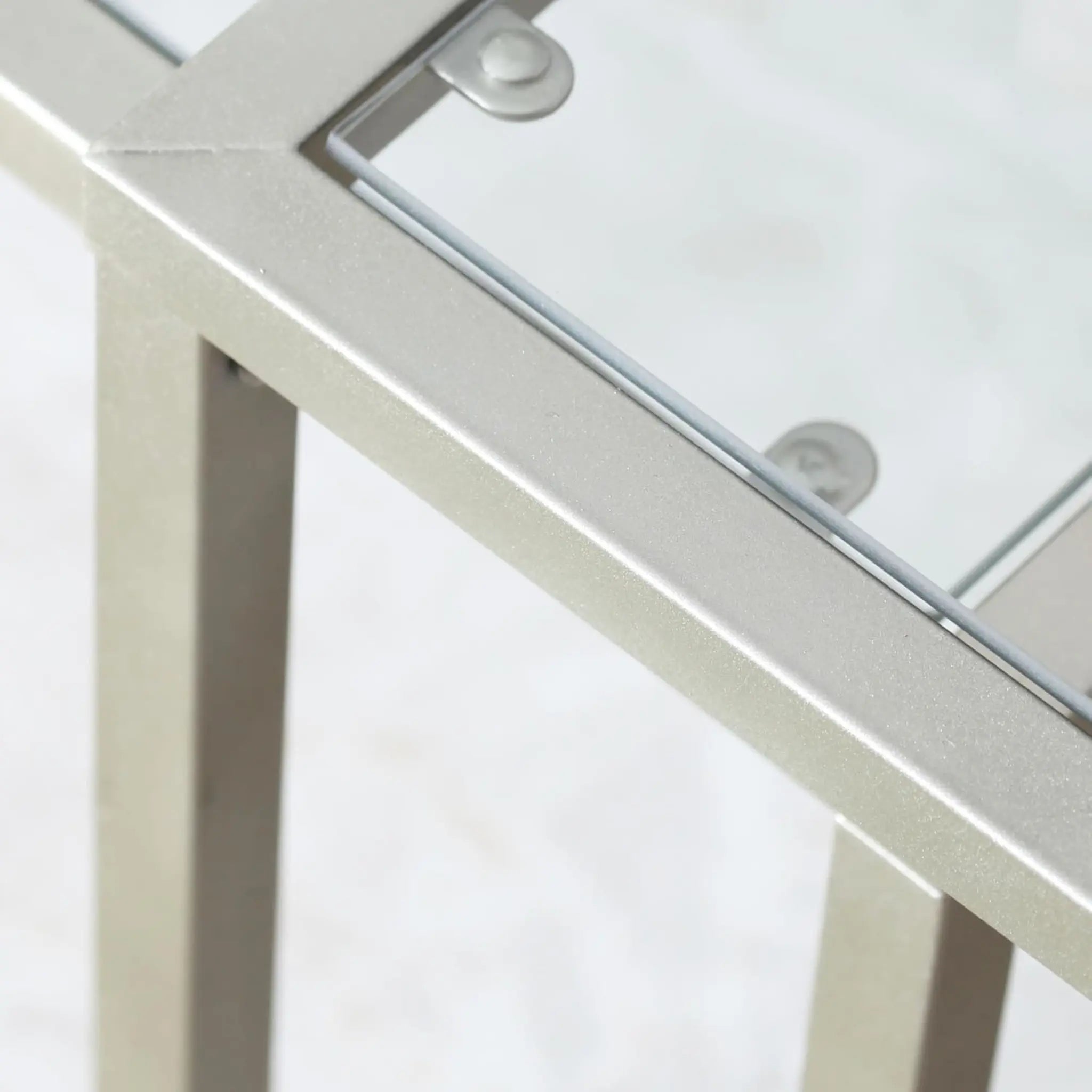 Close-up of a glass-top table with metal legs on a white background
