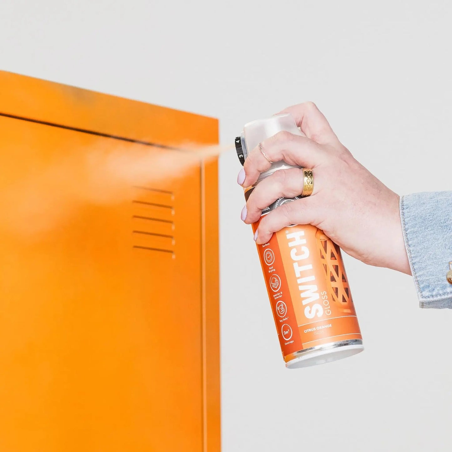 Person holding an orange spray can labeled 'Switch' against a white background