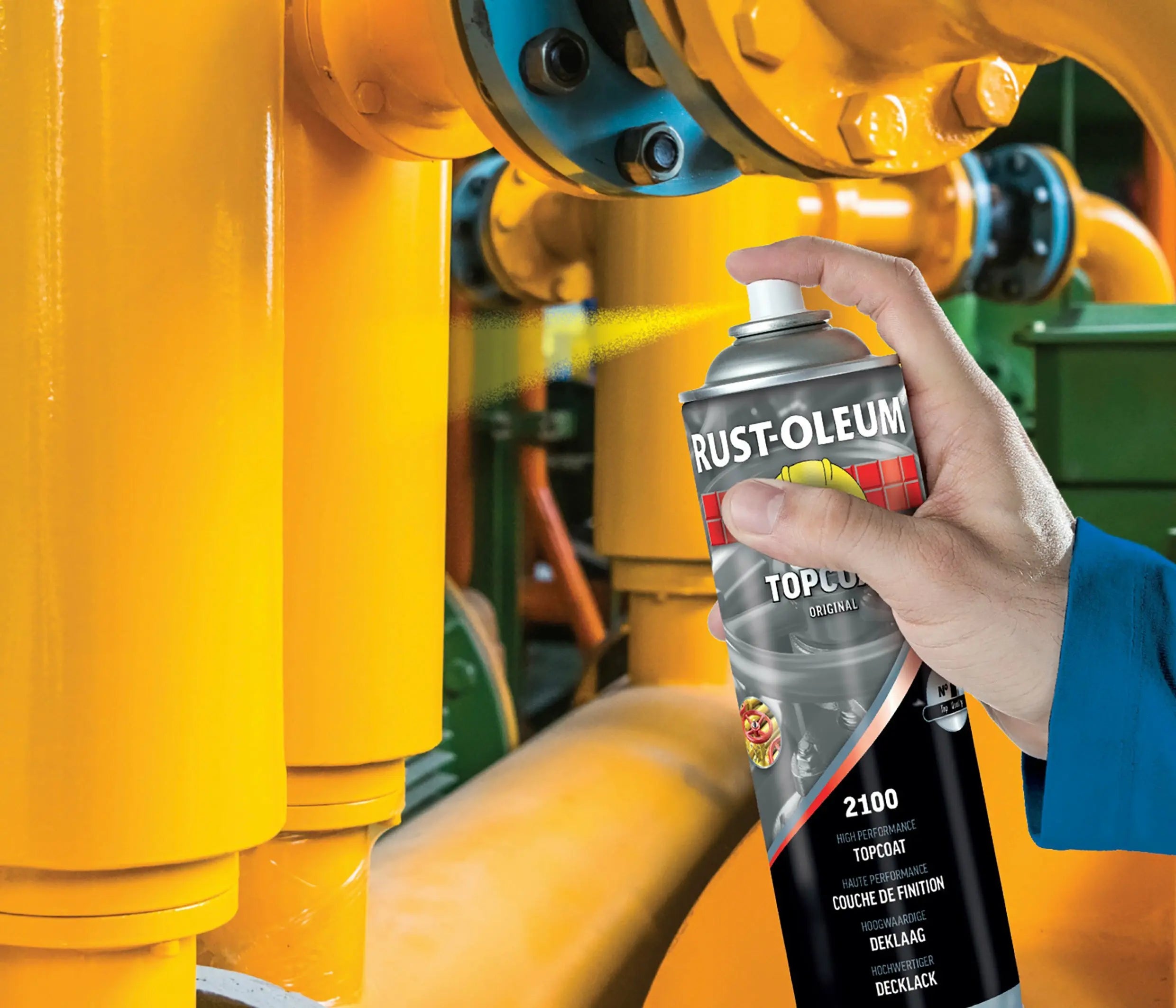 Hand holding a Rust-Oleum spray can over a yellow industrial pump.